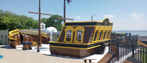 A pirate-themed play area with a ship structure, a lifebuoy, and a small pool.