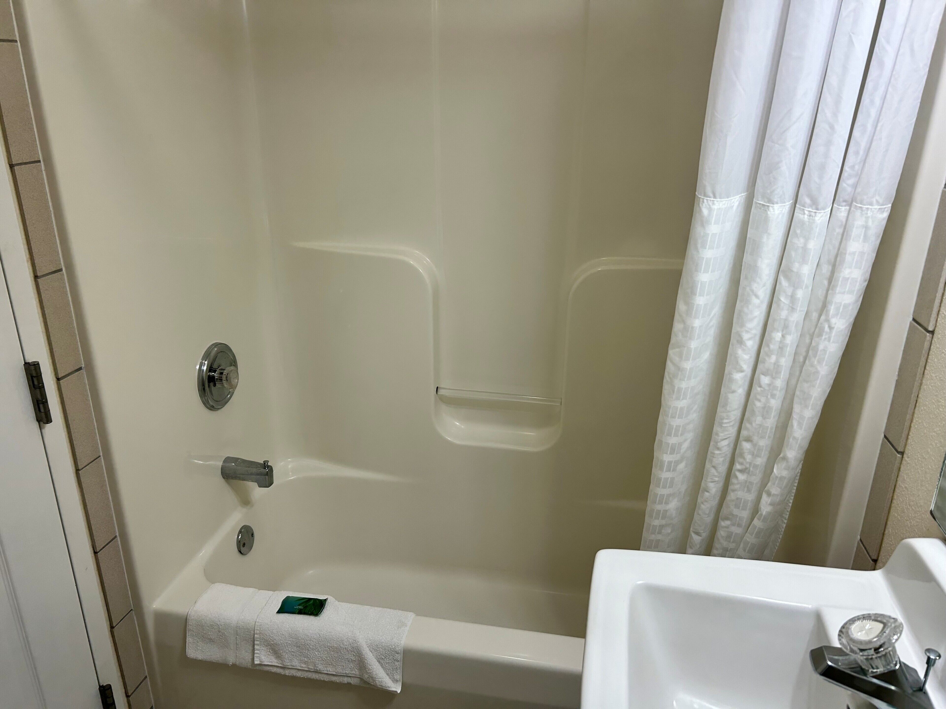 A bathroom with a bathtub, a shower curtain, a towel rack, and a sink.