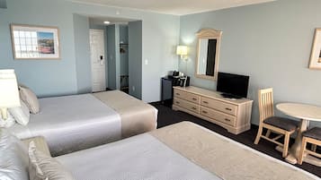 Une chambre d’hôtel avec deux lits, un bureau, une chaise, une commode, une télévision et un miroir.