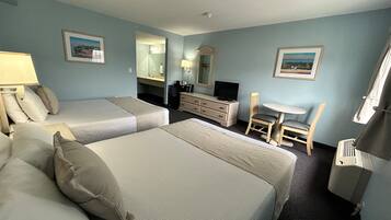 A hotel room with two beds, a desk, a chair, a dresser, a TV, and two framed pictures on the walls.