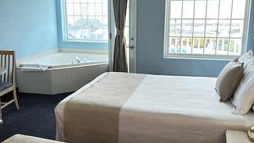 Ein Hotelzimmer mit einem großen Bett, einem Einzelbett, einer Badewanne und einem Fenster mit Blick.