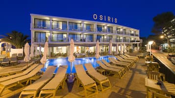 A hotel with a pool area, sun loungers, and outdoor seating.