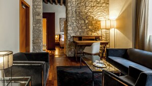Una sala de estar moderna con pared de piedra, un escritorio de madera, un sofá de cuero negro y una mesa de centro de vidrio.