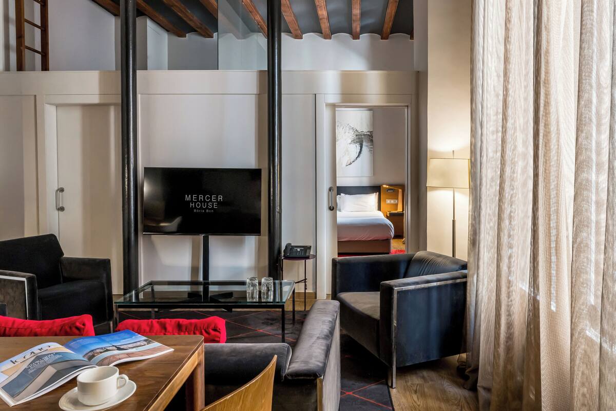 Ein Hotelzimmer mit Fernseher, Bett, Sofa, Couchtisch und Esstisch.