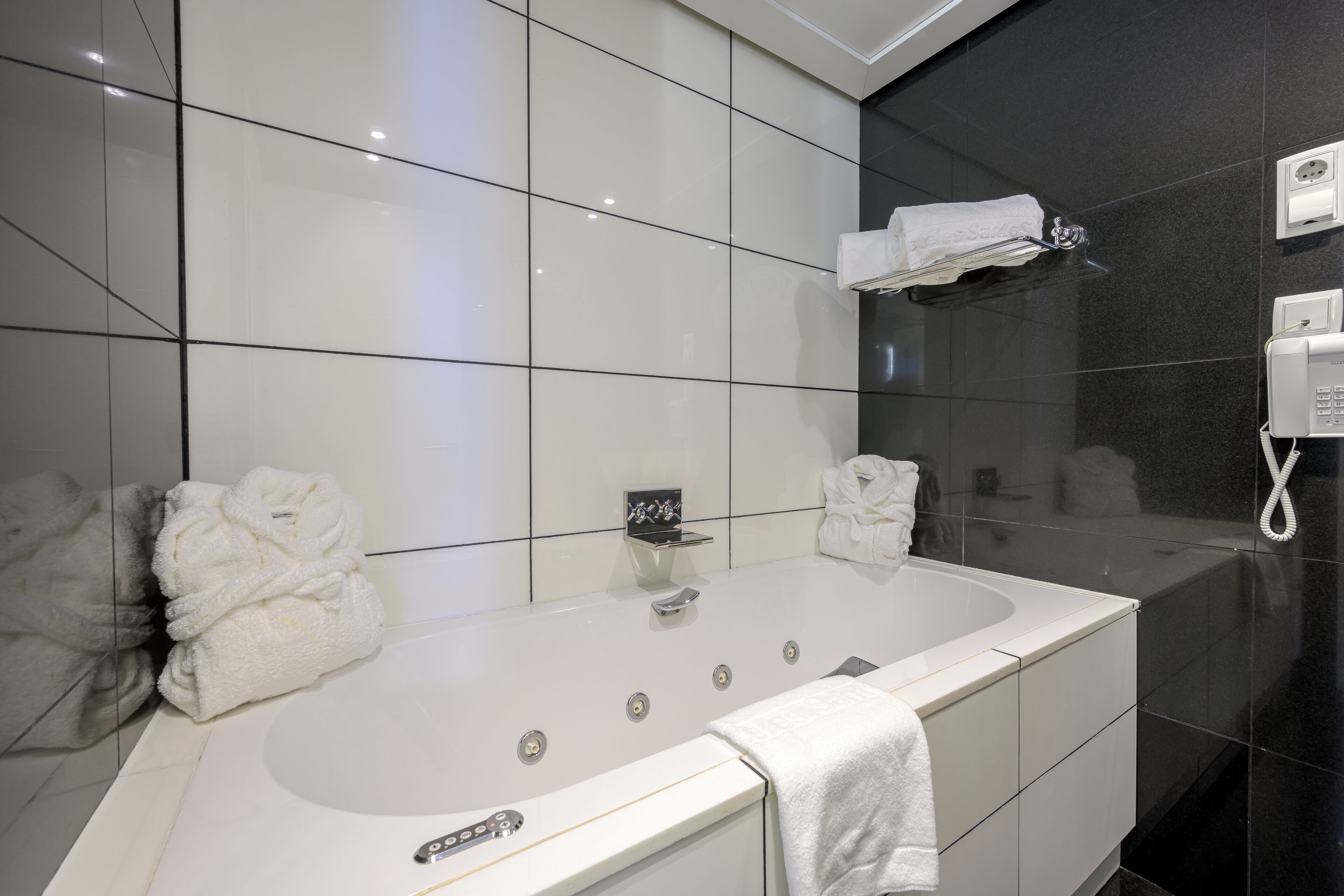 A modern bathroom with a large bathtub, a glass shower enclosure, and a towel rack.