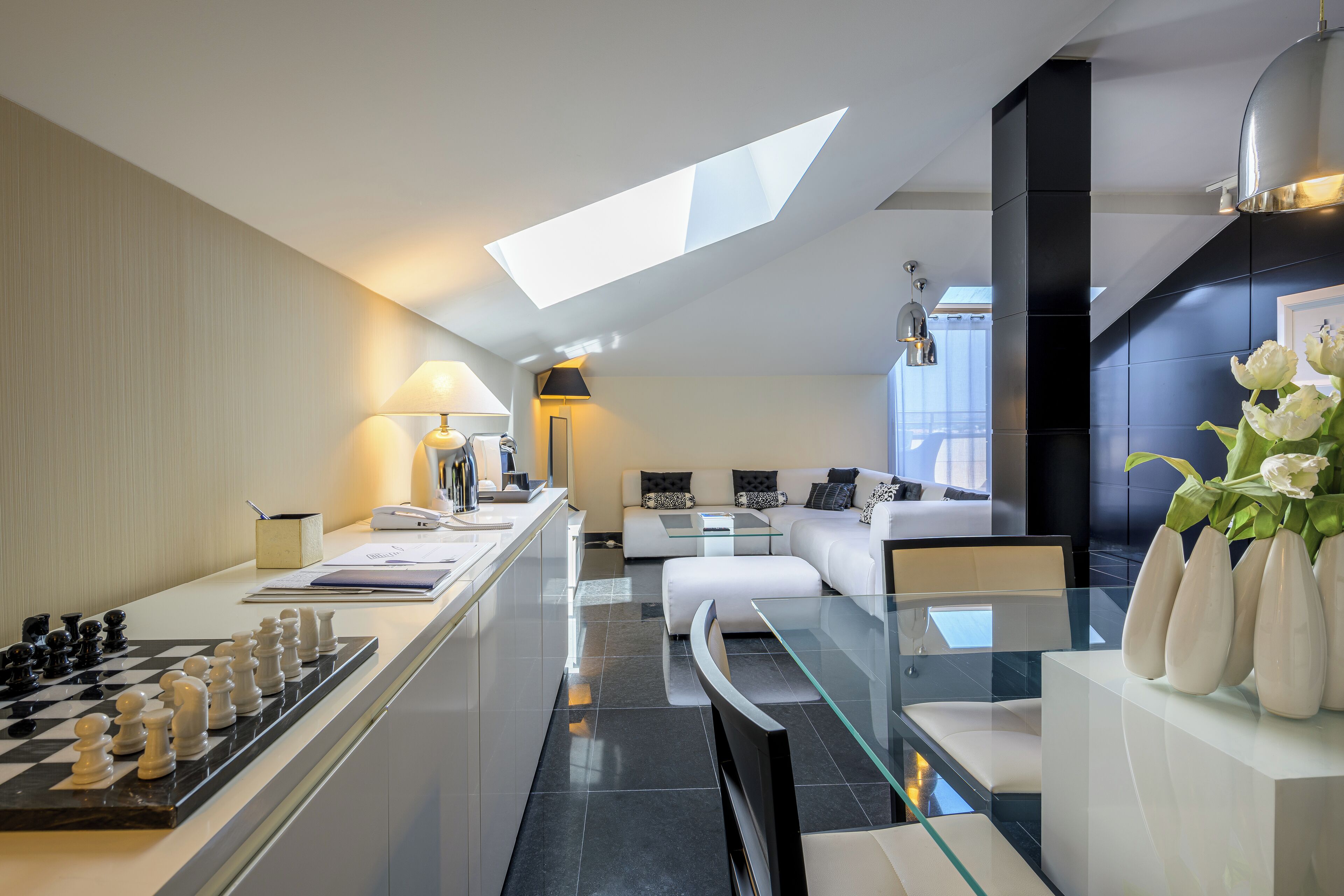 A modern kitchen with a chessboard, a dining area with a glass table, and a sofa set.