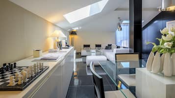 A modern kitchen with a chessboard, a dining area with a glass table, and a sofa set.