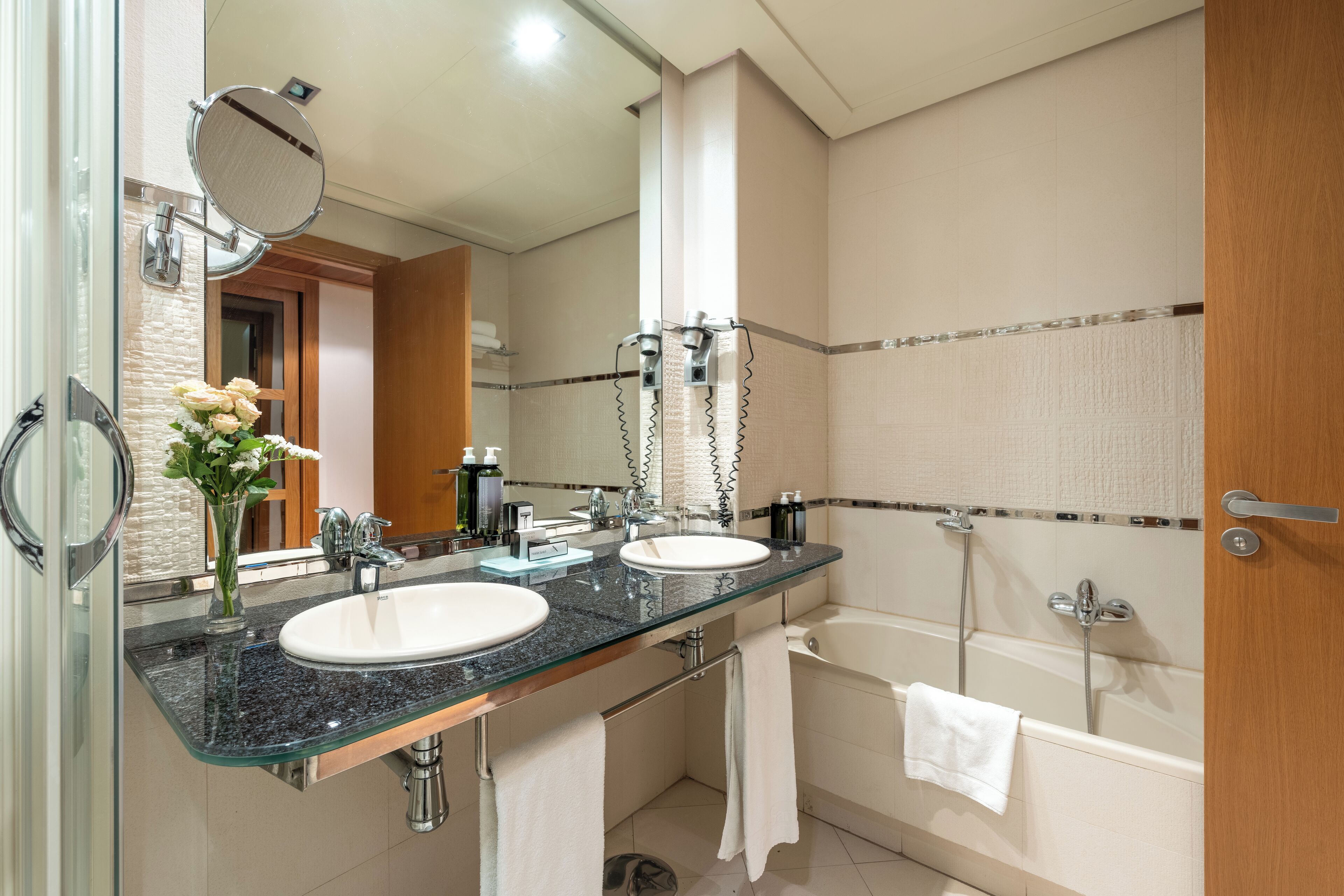 Un baño moderno con dos lavamanos, un espejo grande y una bañera.