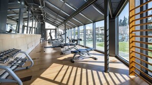 Une salle de sport équipée de matériel d’exercice, dotée de grandes fenêtres et d’un plancher en bois.