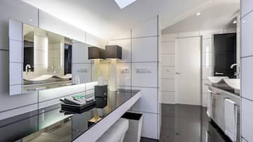 Une salle de bain moderne avec un grand miroir, un plan de travail noir et un mur recouvert de carreaux blancs.