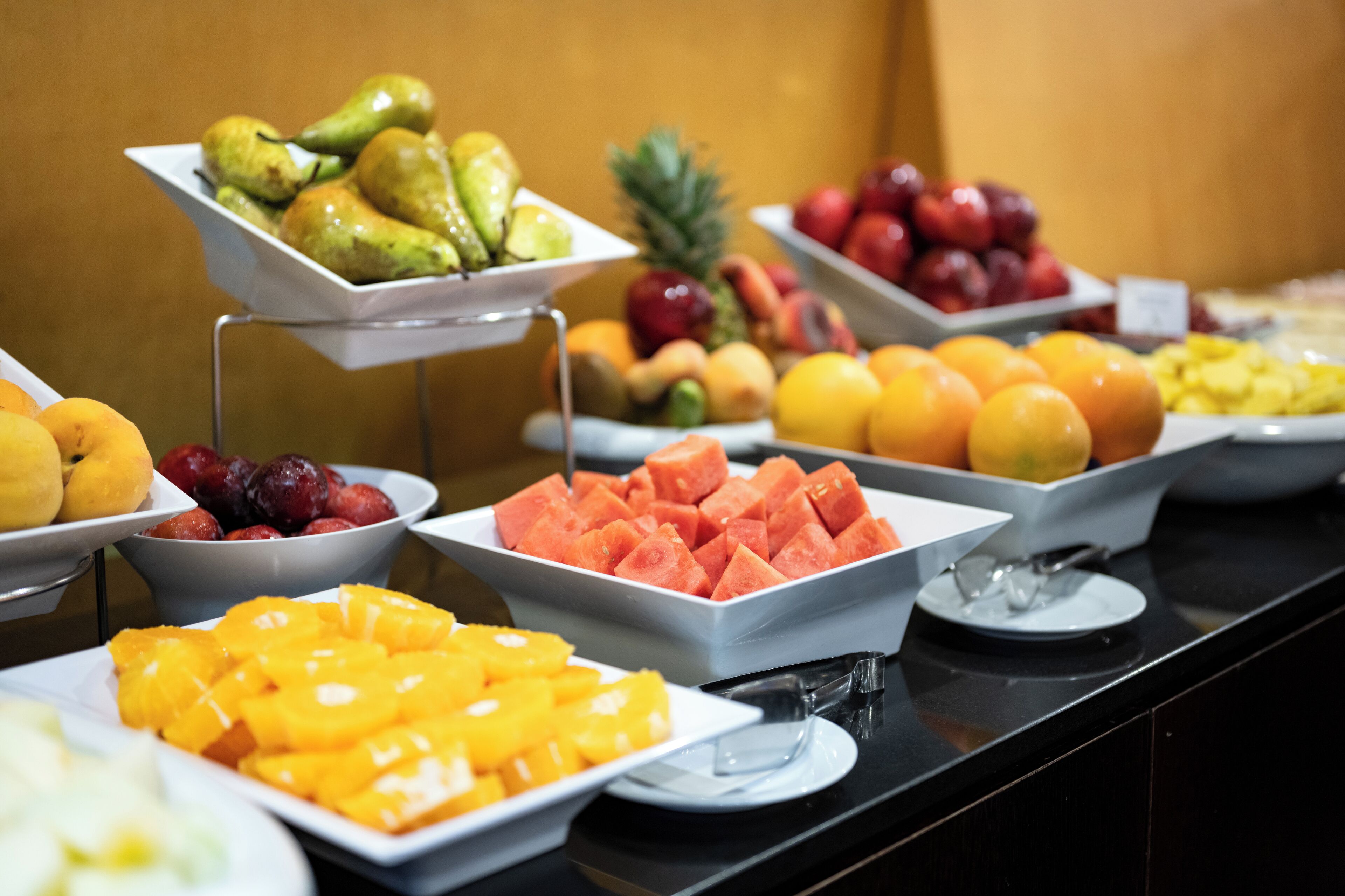 Un bufé con diversas frutas y verduras dispuestas en bandejas.