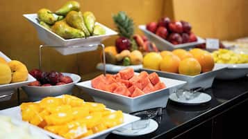 Un bufé con diversas frutas y verduras dispuestas en bandejas.