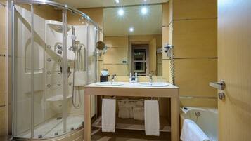 A bathroom with a glass-enclosed shower, two sinks, a bathtub, and a mirror above the sinks.