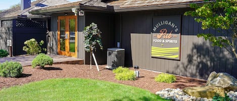 A building with a sign reading "Mulligan's Pub Food & Spirits" and a small outdoor seating area with a fire pit.