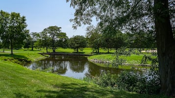 A serene park with a pond, lush greenery, and a bridge.