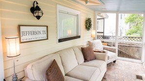 Ein gemütlicher Sitzbereich mit einer beigefarbenen Couch, einem Schild mit der Aufschrift "JEFFERSON, TX", einer Wandleuchte und einem Willkommensschild.