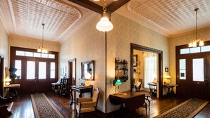 Ein geräumiges Zimmer mit Holzböden, einem großen Spiegel, einem Schreibtisch und einem Stuhl. Es gibt zwei Türen und ein Fenster.