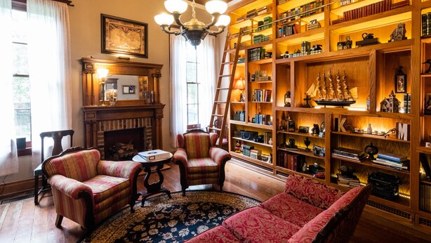 Eine Bibliothek mit Bücherregalen, einem Kamin und klassischen Möbeln.