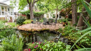 Eine Gartenpatio mit Gartenmöbeln, einem Teich und umgebendem Grün.