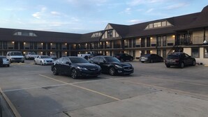 A motel with a parking lot filled with various cars. The building has multiple balconies and a flat roof. - Executive Inn (Edmond)