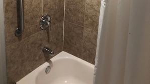 A bathroom with a bathtub, a showerhead, and a handrail. - Executive Inn (Edmond)