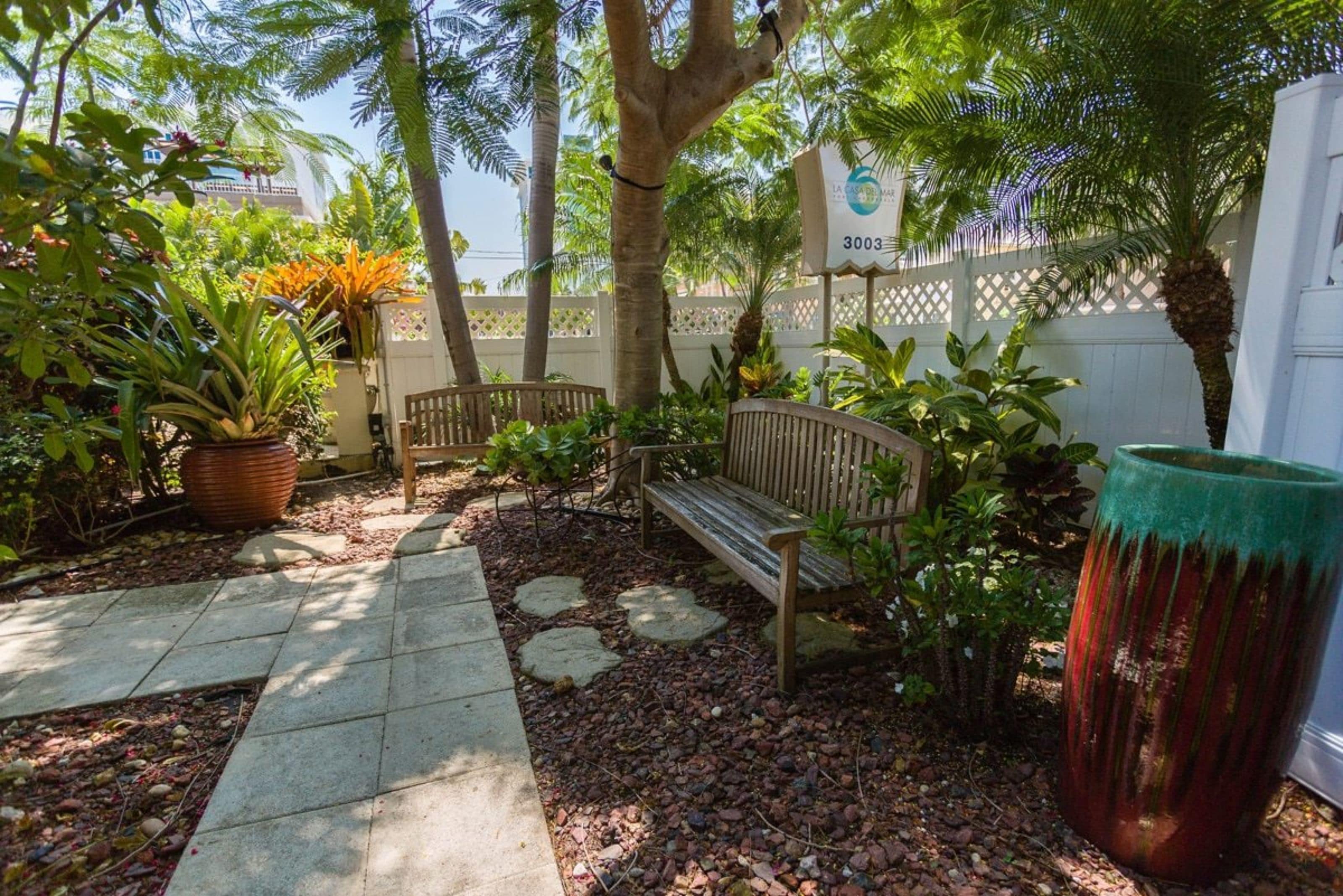 A patio area with a wooden bench, potted plants, and a sign indicating the property number 3003.