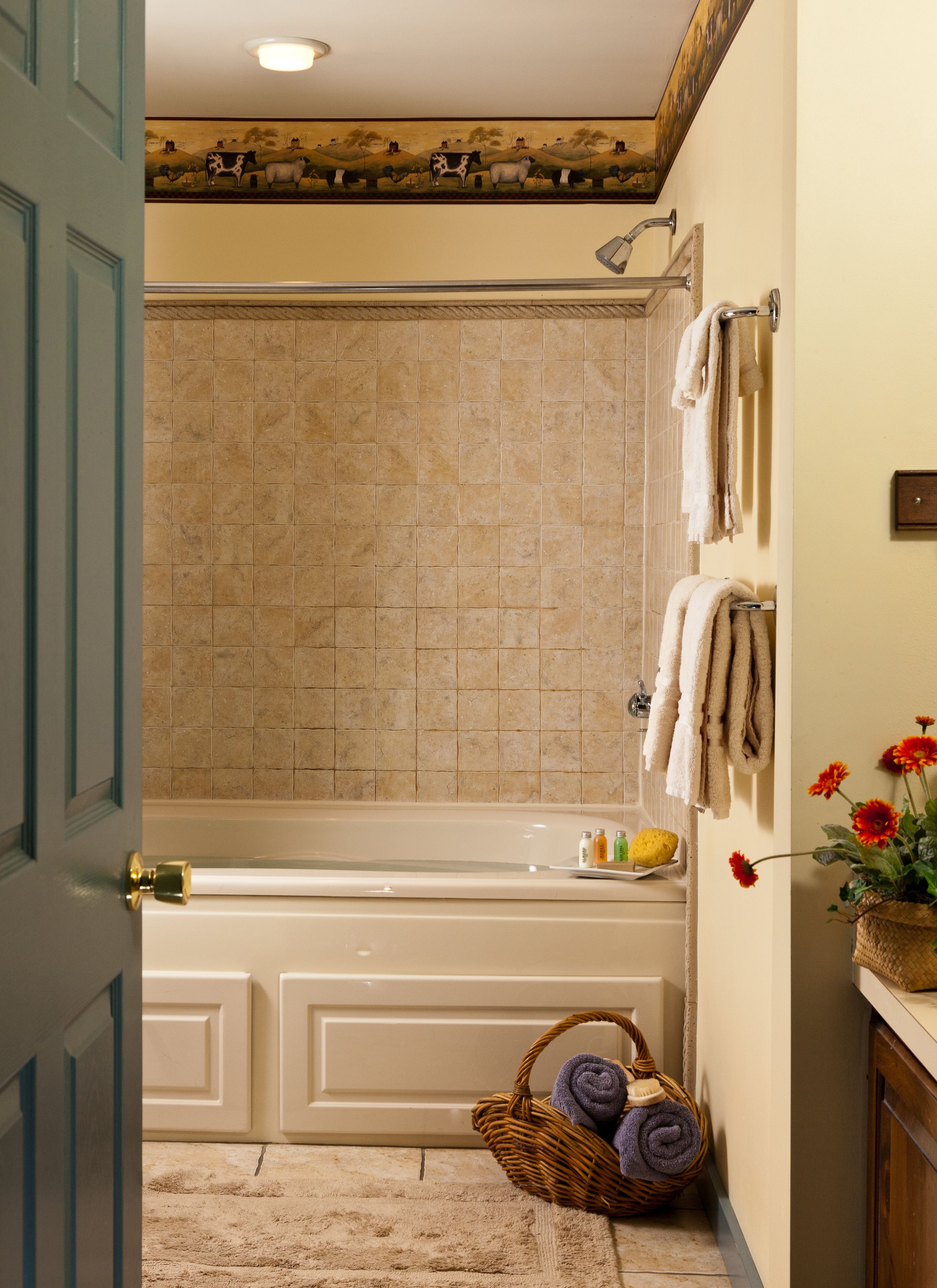 Un baño con bañera, ducha y lavamanos. Hay toallas y una cesta con toallas en el suelo.