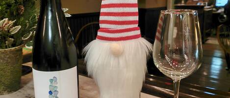 A bottle of Seaglass Riesling wine, a gnome figure with a red and white striped hat, and an empty wine glass on a marble countertop.