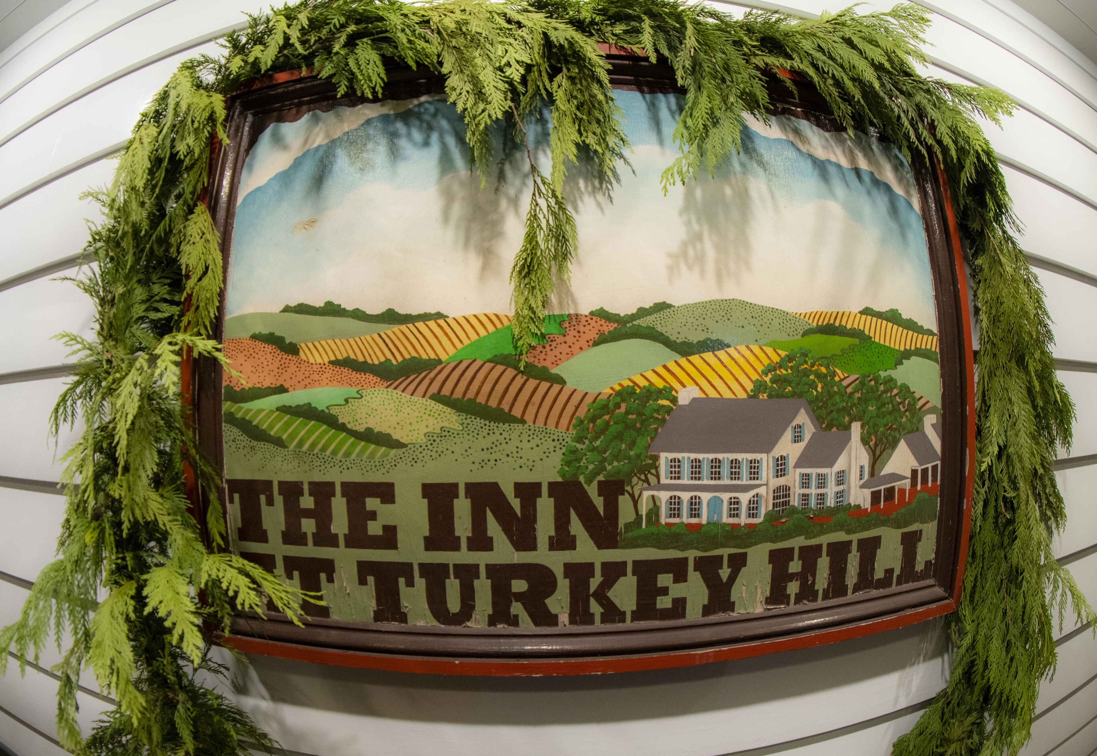 Un letrero enmarcado con una ilustración de paisaje y el texto 'The Inn at Turkey Hill'.