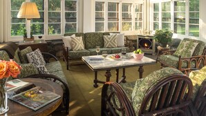 A cozy room with a fireplace, comfortable seating, and large windows offering a view of the outdoors.