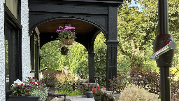 A patio with a round metal table, a glass of white wine, and a red umbrella. - Manor House Inn (Norfolk)