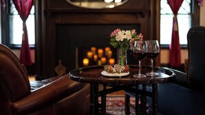 A dining table with a plate of food and two wine glasses, set in a room with leather furniture and a fireplace in the background. - Manor House Inn (Norfolk)