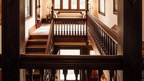 A grand staircase with a wooden railing, leading to a room with large windows and a patterned ceiling. - Manor House Inn (Norfolk)