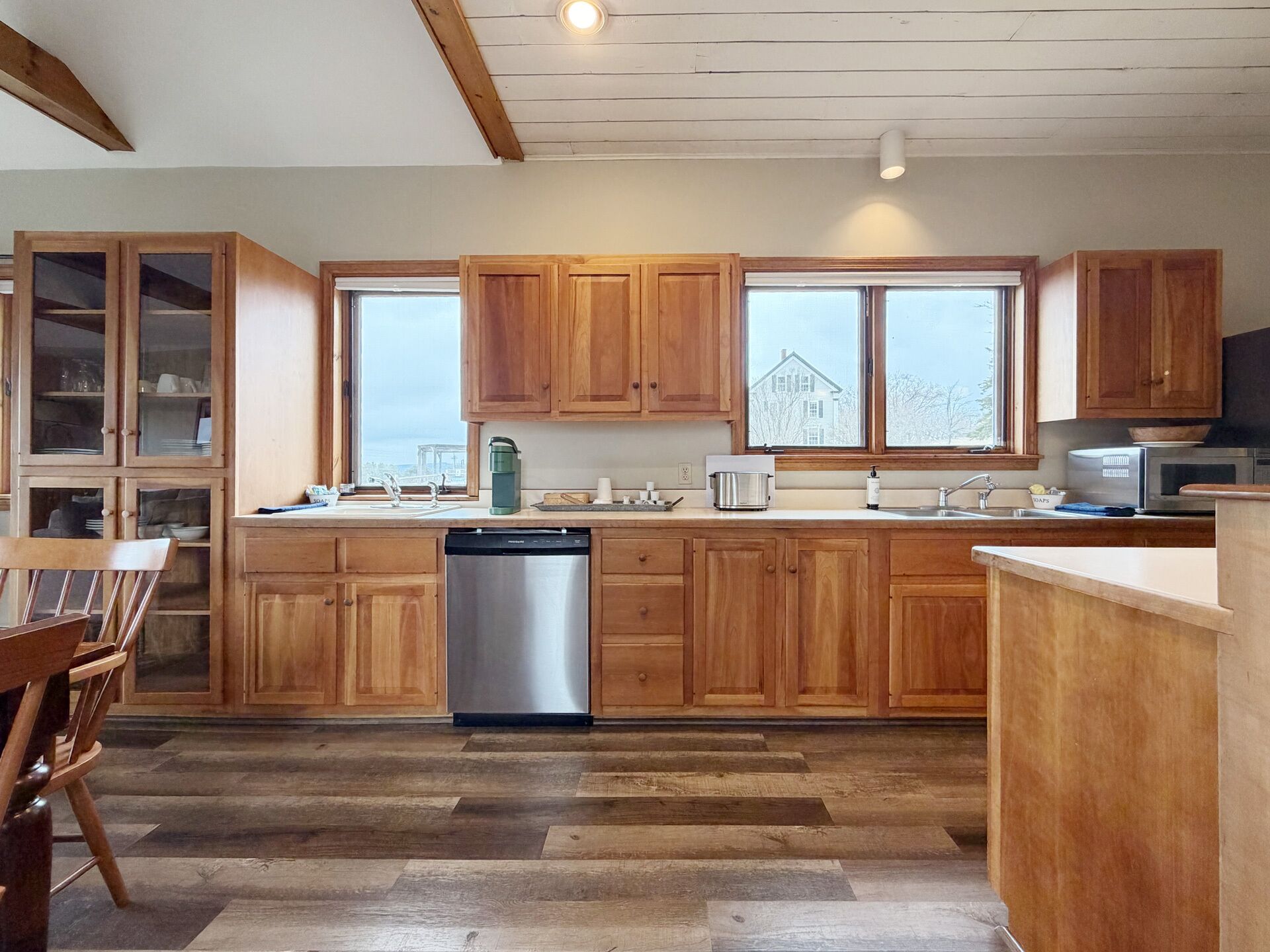 A kitchen with wooden cabinets, a dishwasher, a microwave, and a large window.
