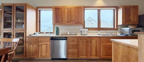 A kitchen with wooden cabinets, a dishwasher, a microwave, and a large window.