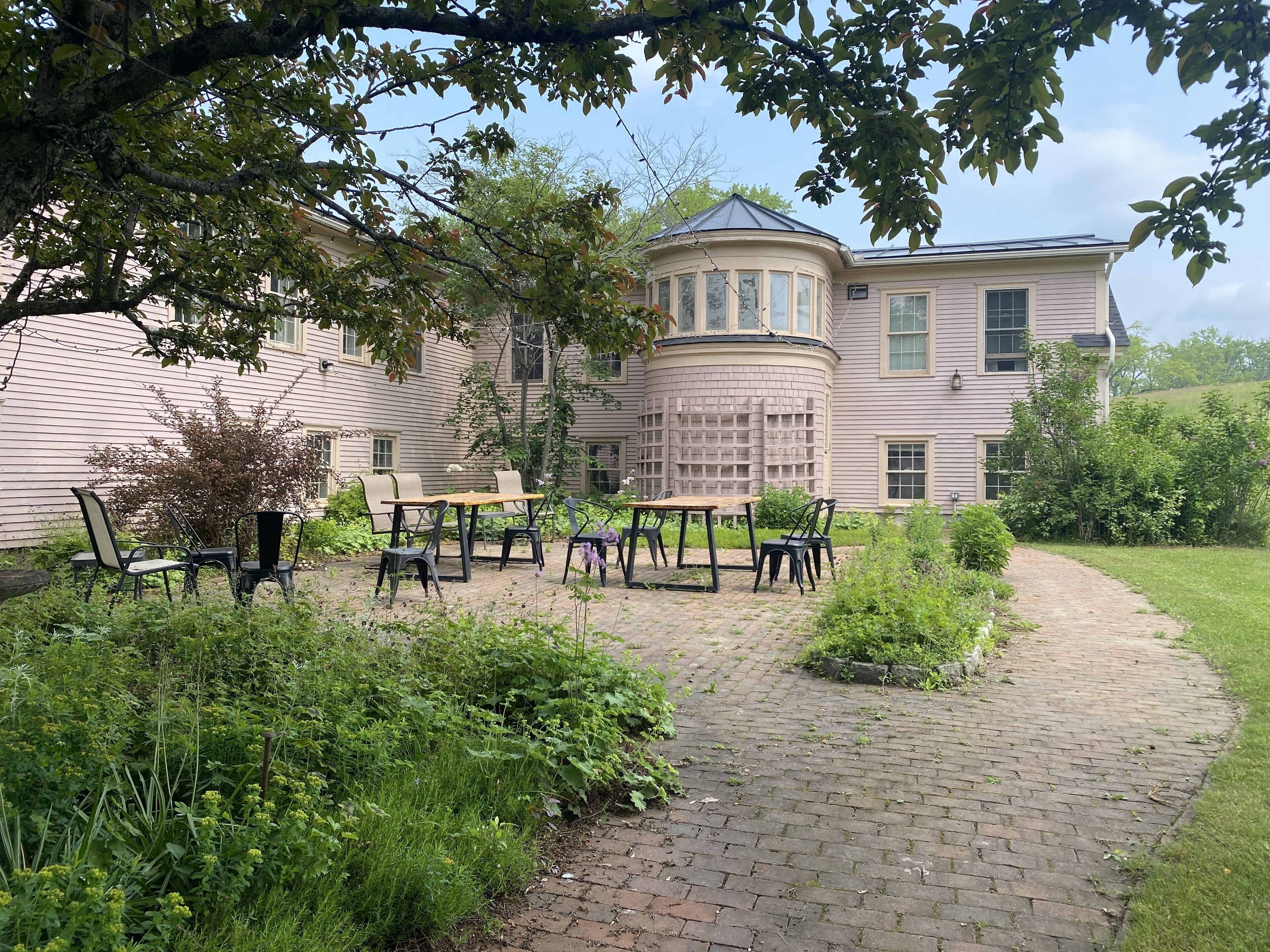 A house with a circular tower, a brick patio, and outdoor furniture.