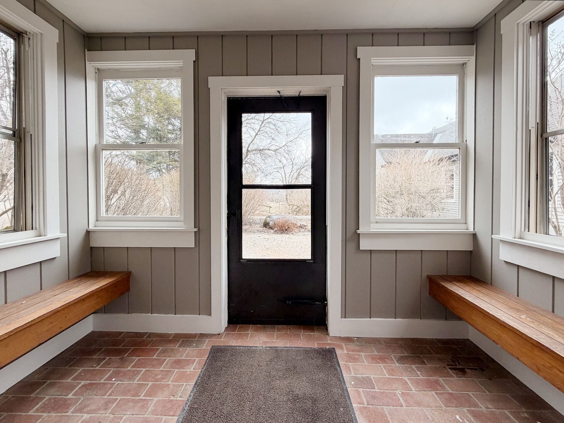 A room with a door, two windows, and a bench.