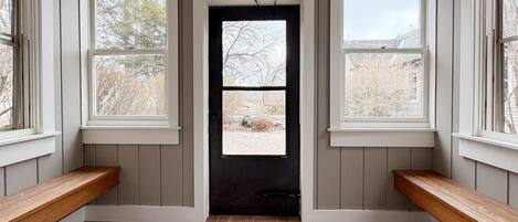 A room with a door, two windows, and a bench.