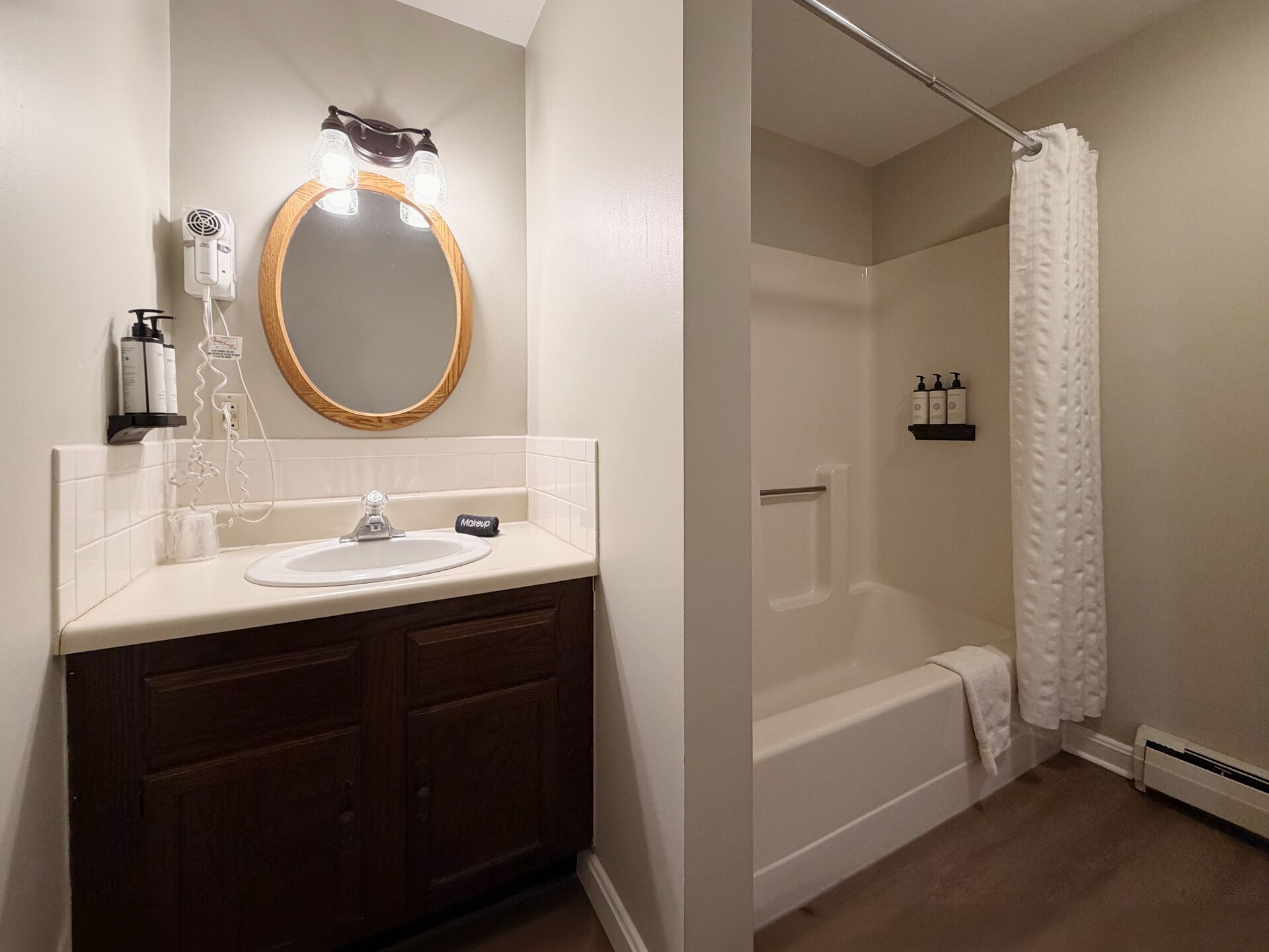 A bathroom with a vanity, a mirror, a towel rack, a shower curtain, and a bathtub.