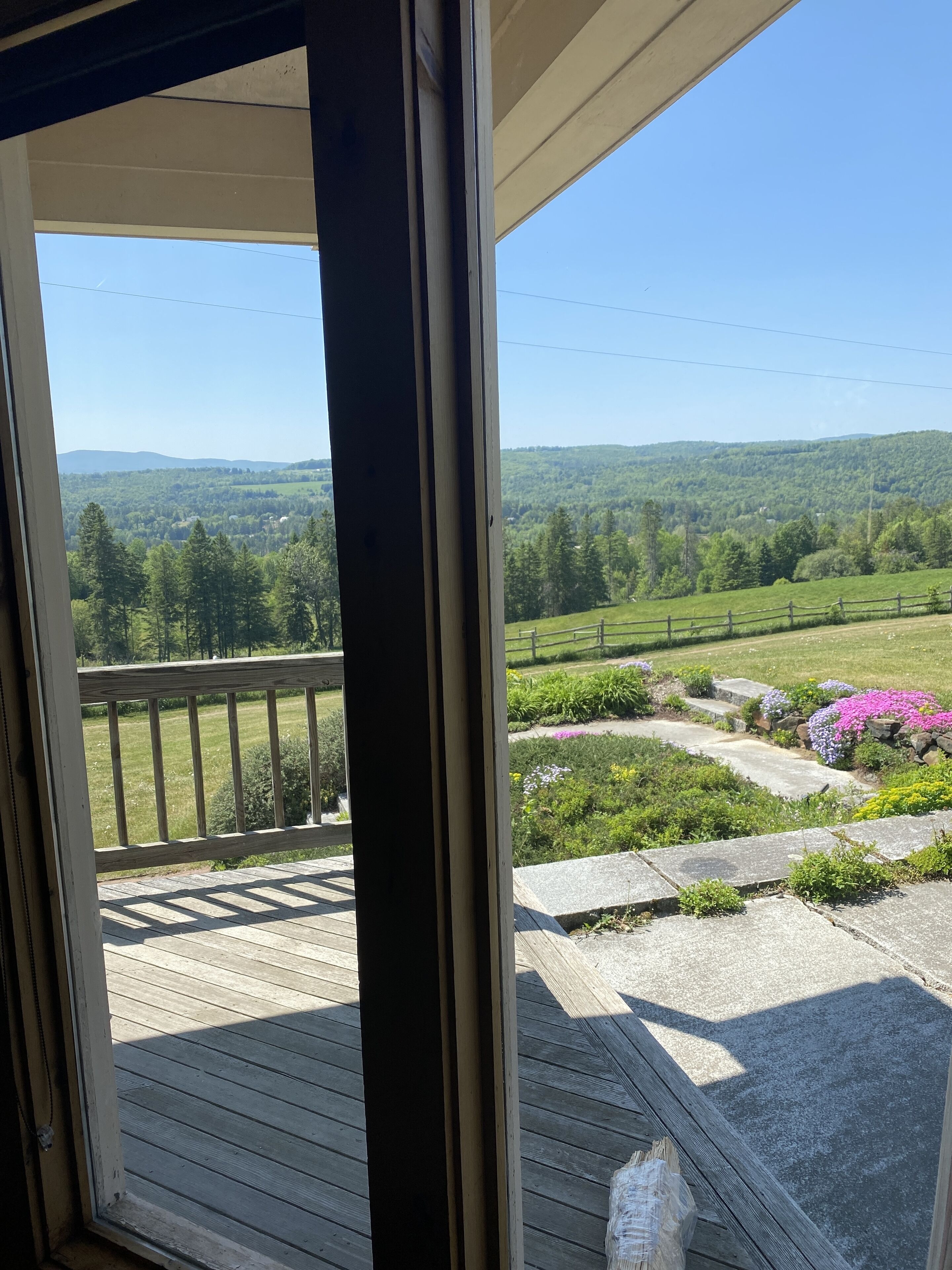 A wooden deck with a view of a green landscape and hills.