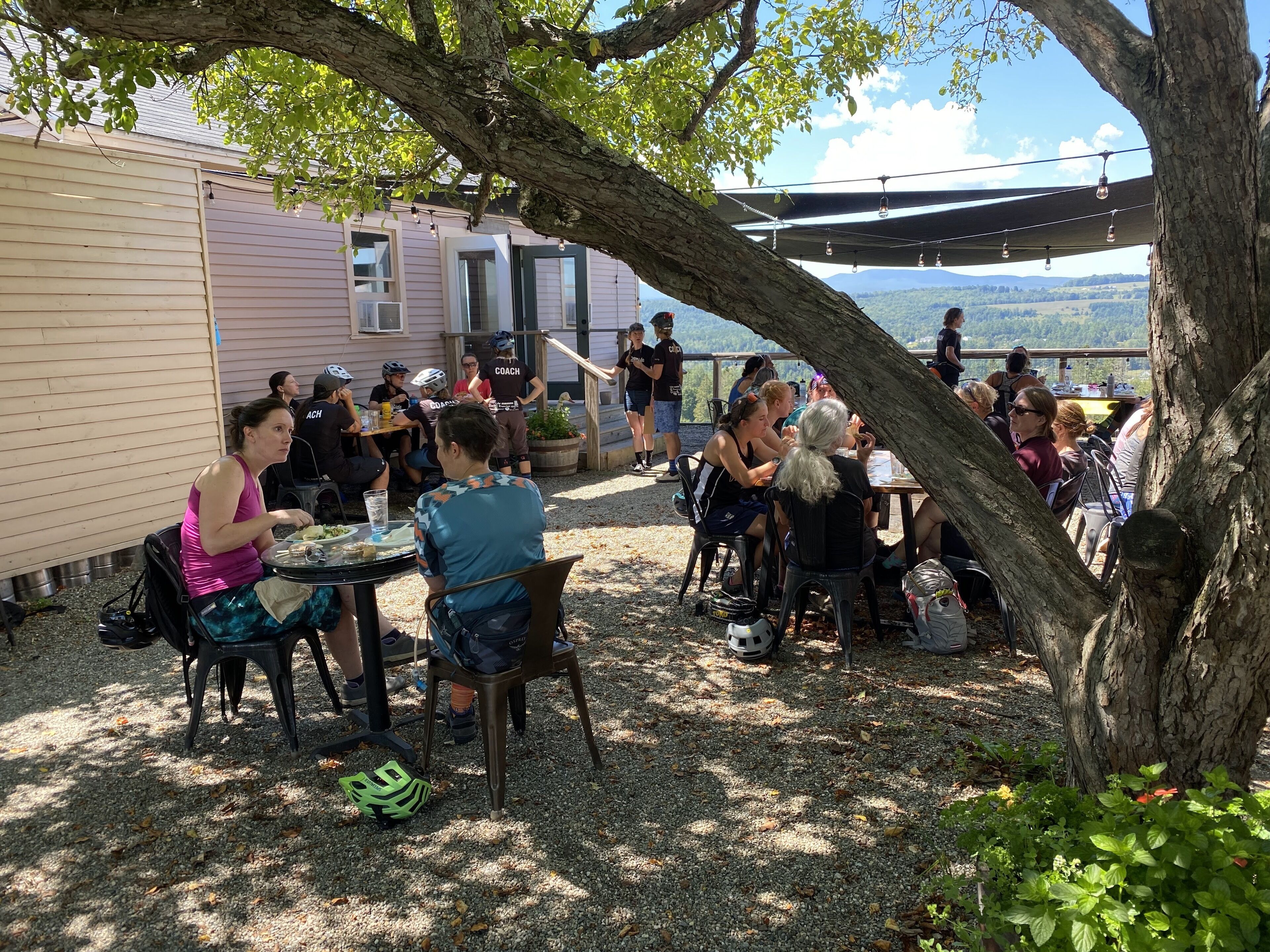 Un espace extérieur aménagé avec des tables et des chaises, un coin salon abrité et une vue sur le paysage.
