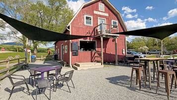 A red building with a sign reading 'BIKE SHOP' and a gravel patio with tables and chairs.