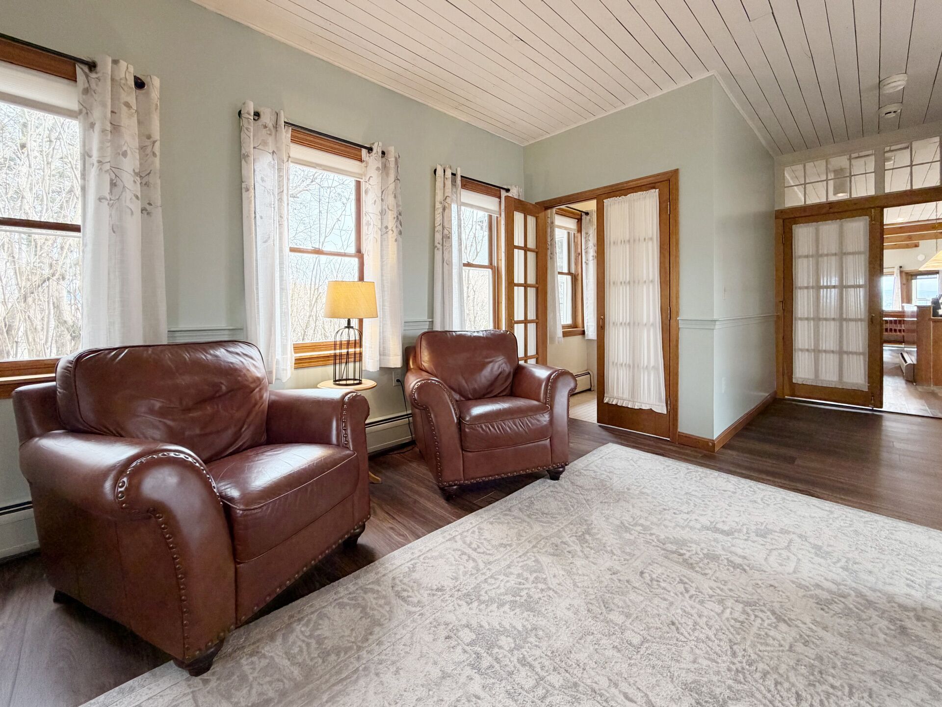 A room with two leather armchairs, a patterned rug, and a lamp on a side table.