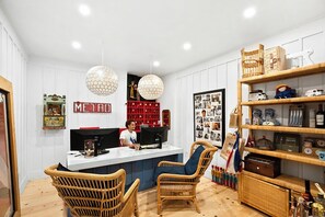 A cozy room with a reception desk, wicker chairs, a bookshelf, and a wall with a 'METRO' sign. - Metro Hotel and Cafe (Petaluma)