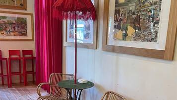 Une pièce avec un plancher en bois, des chaises en osier, une petite table ronde et un parapluie rouge.