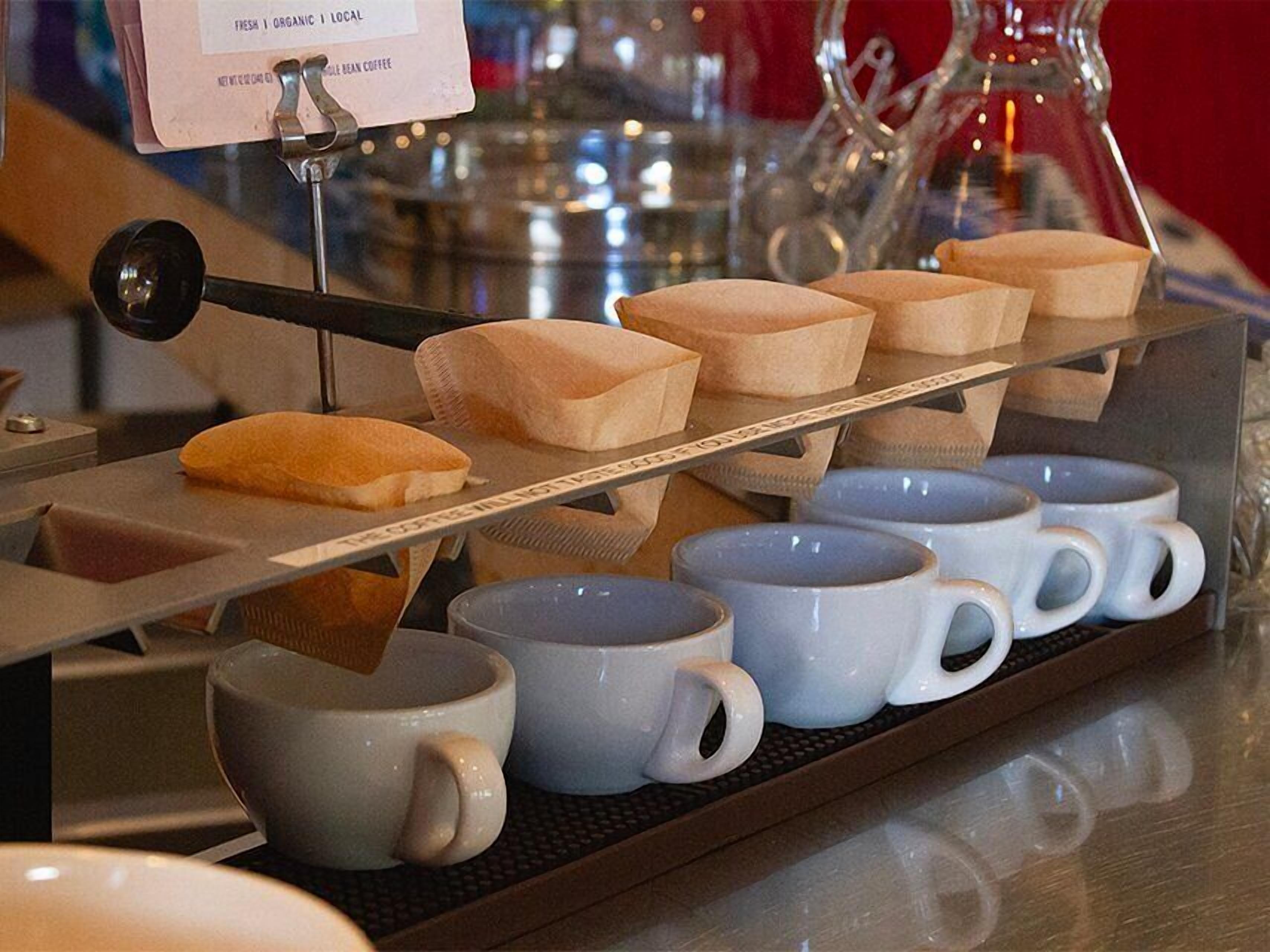 A coffee machine with a sign indicating it serves fresh, organic, local coffee.