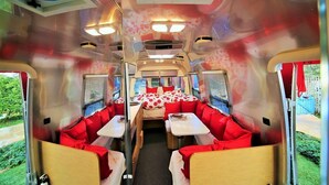 A camper van interior with a bed, seating area, and tables. - Metro Hotel and Cafe (Petaluma)