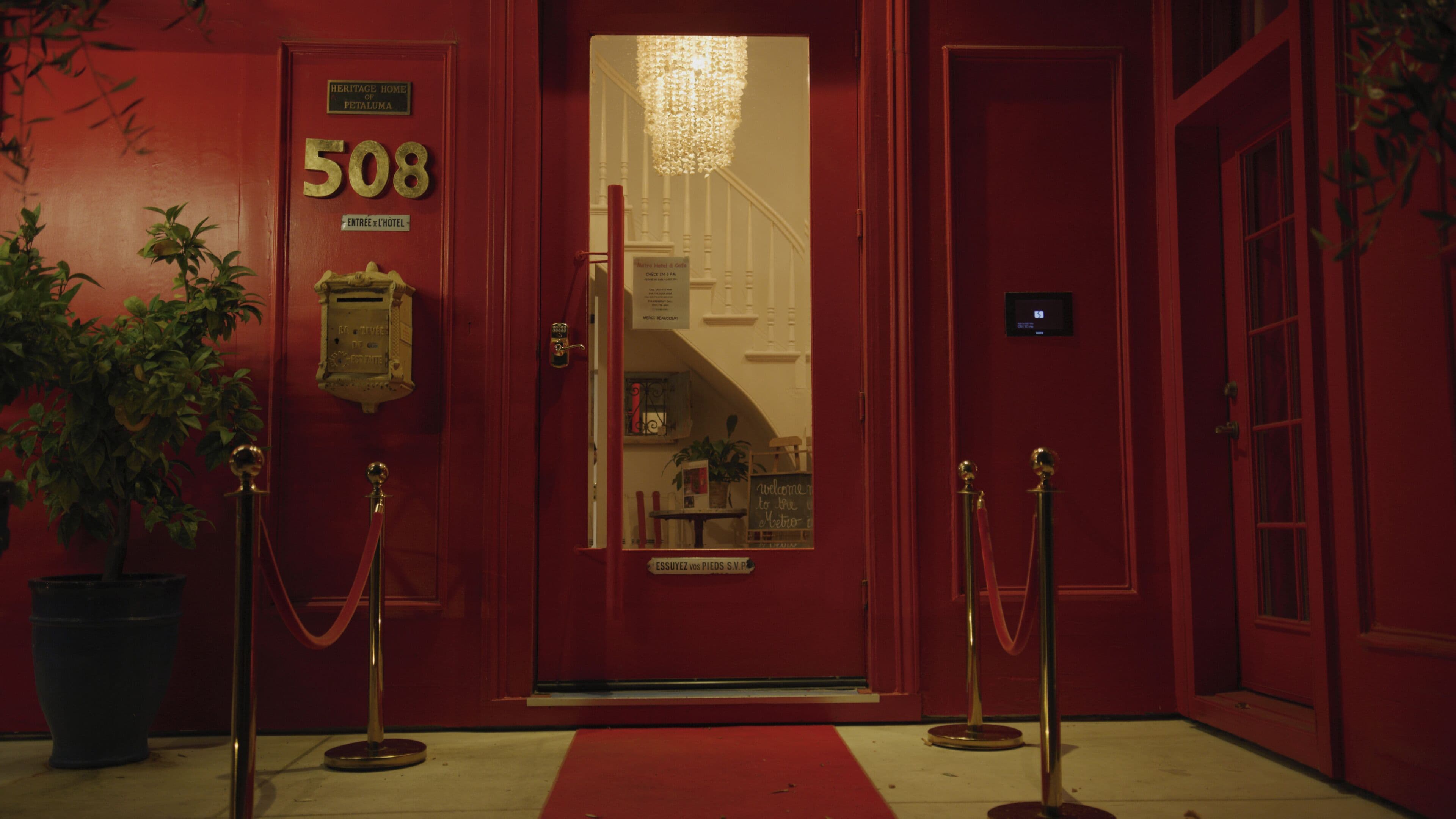 Une porte rouge portant le numéro 508, une enseigne indiquant « Heritage Home of Petaluma », et un tapis rouge menant à l’entrée.