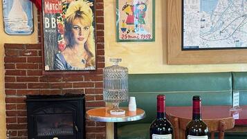 A cozy bar area with a brick fireplace, a map on the wall, and two bottles of wine on a tray.