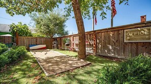 A backyard with a wooden fence, a sign reading "OFFICE", and a barbecue area. - Metro Hotel and Cafe (Petaluma)